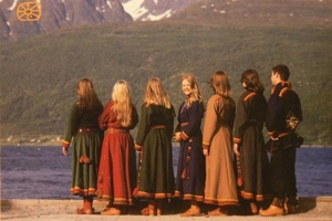 Ungdommer i lyngenkofte som står på rekke med ryggen til med utsikt over fjorden