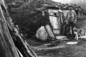 Nils Peder Nilsen og en hund utenfor boliggammen, visstnok den siste i Lyngen, revet i 1950. Stordalen 1948. Foto: